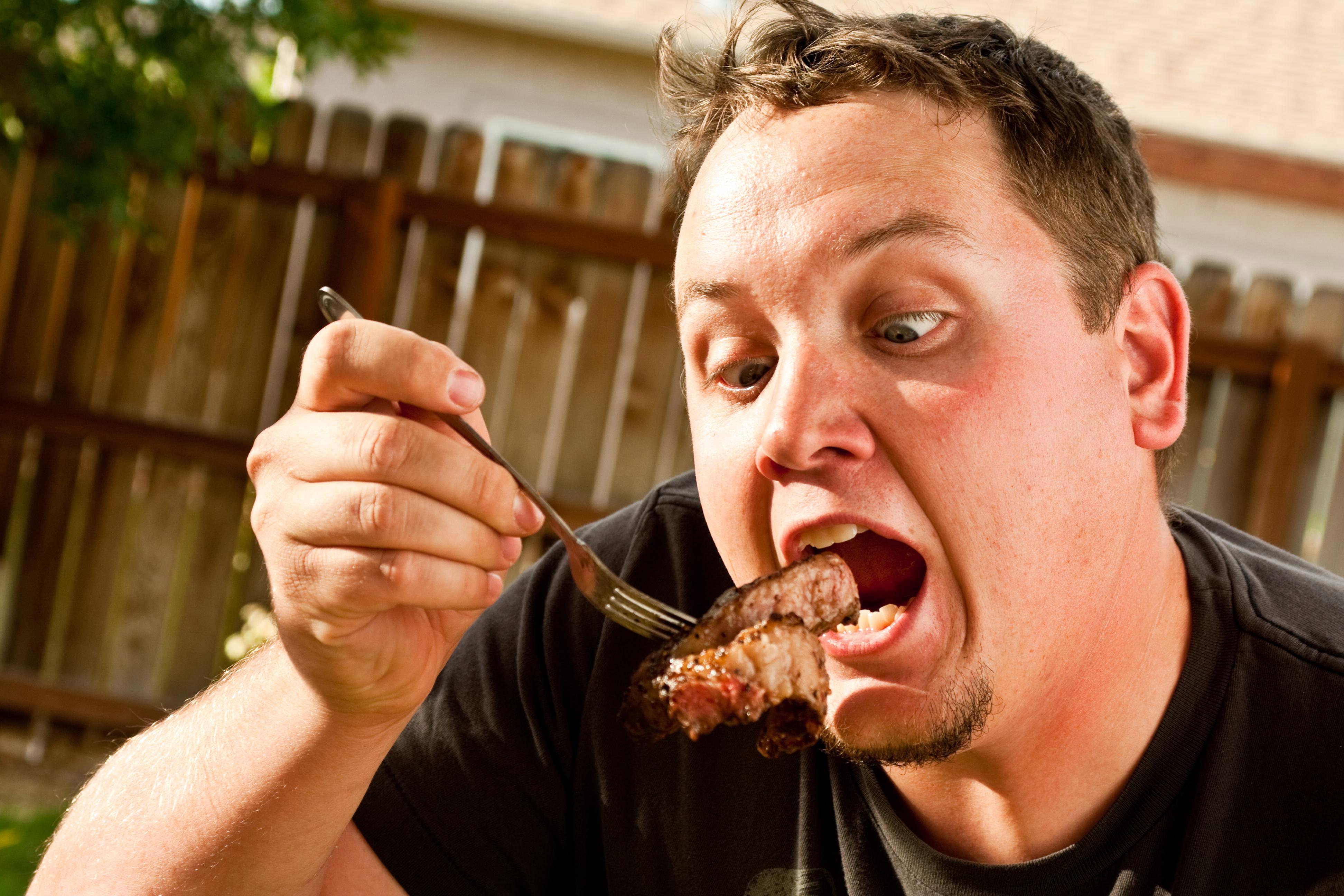 Есть мясо с ножа. Мужчина ест. Человек кушает.