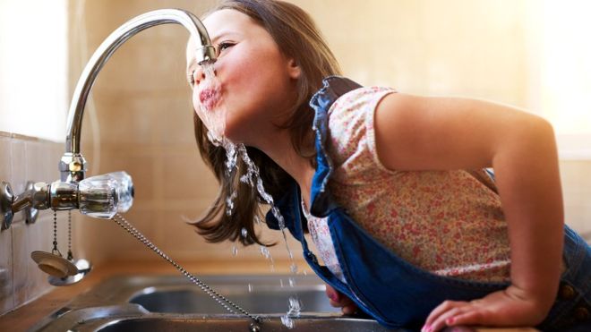 Девочка пьет воду из крана