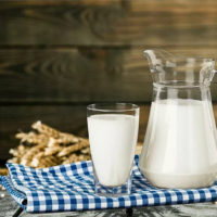 Кувшин и стакан с молоком на клетчатой скатерти