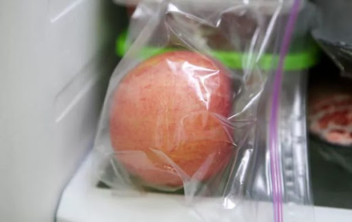 Целое яблоко в полиэтиленовом пакете в холодильнике