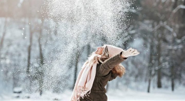 Смеющаяся девушка подбрасывает снег вверх