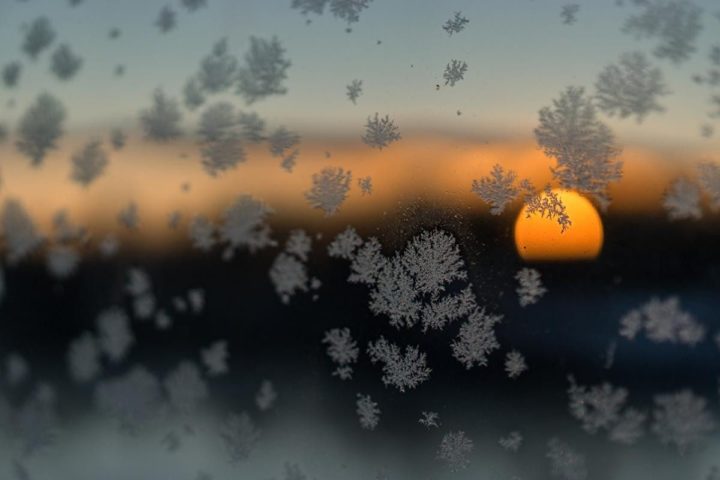 Снежинки на стекле на фоне садящегося солнца